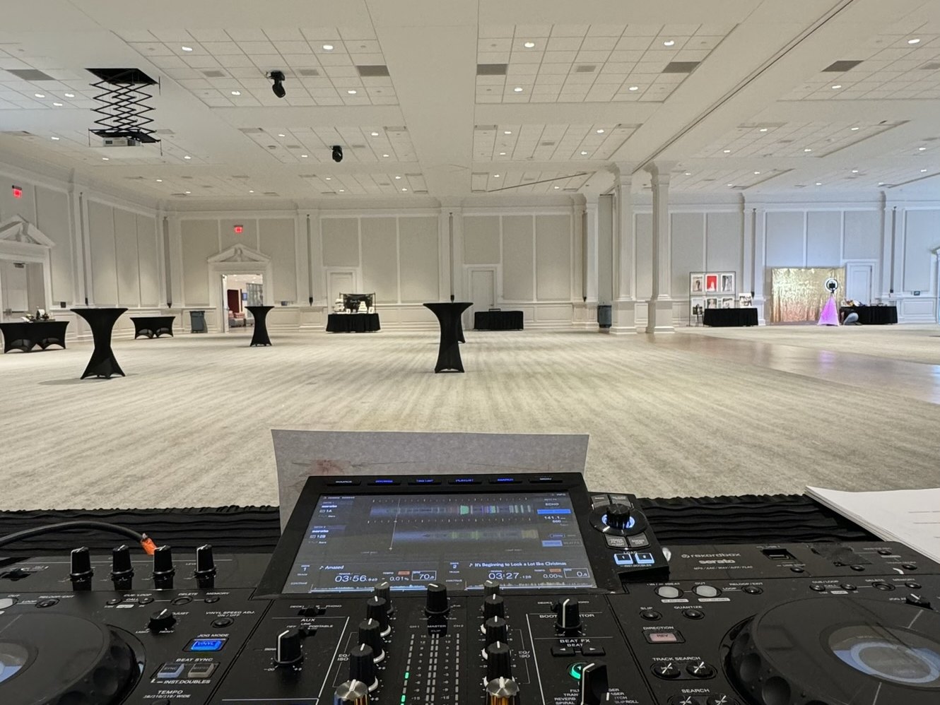 An all in one DJ controller on a booth at the edge of an empty ballroom floor