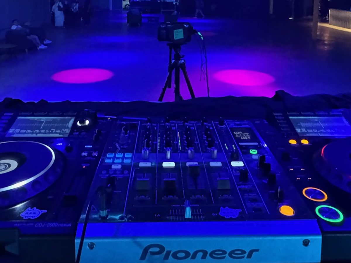 A Pioneer DJ DJM-900NXS2 mixer between four players under blue light in an empty Dallas venue before doors