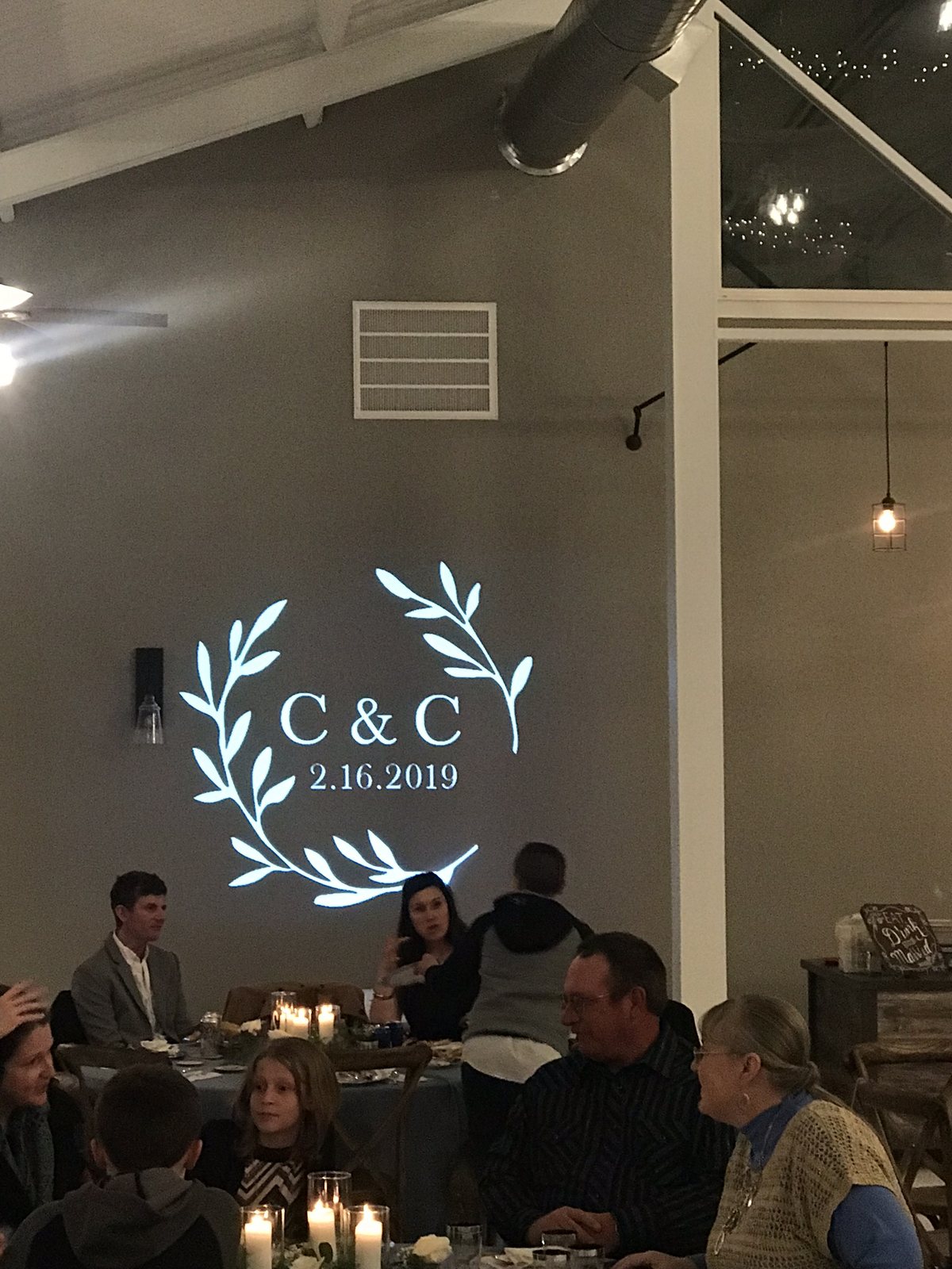 A white CR wedding monogram projected on the wall above the head table at a DFW reception