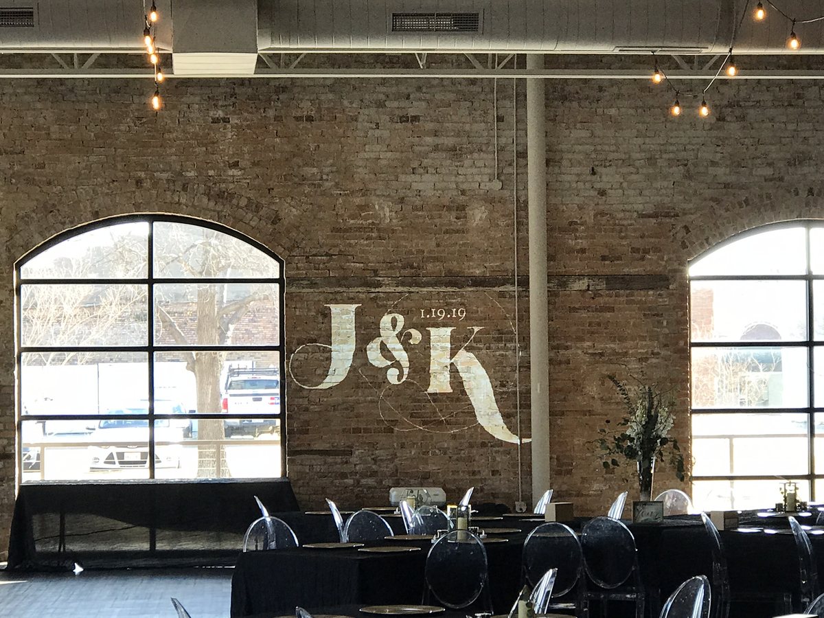 A full color gold and floral wedding monogram projected on a board and batten wall in daylight