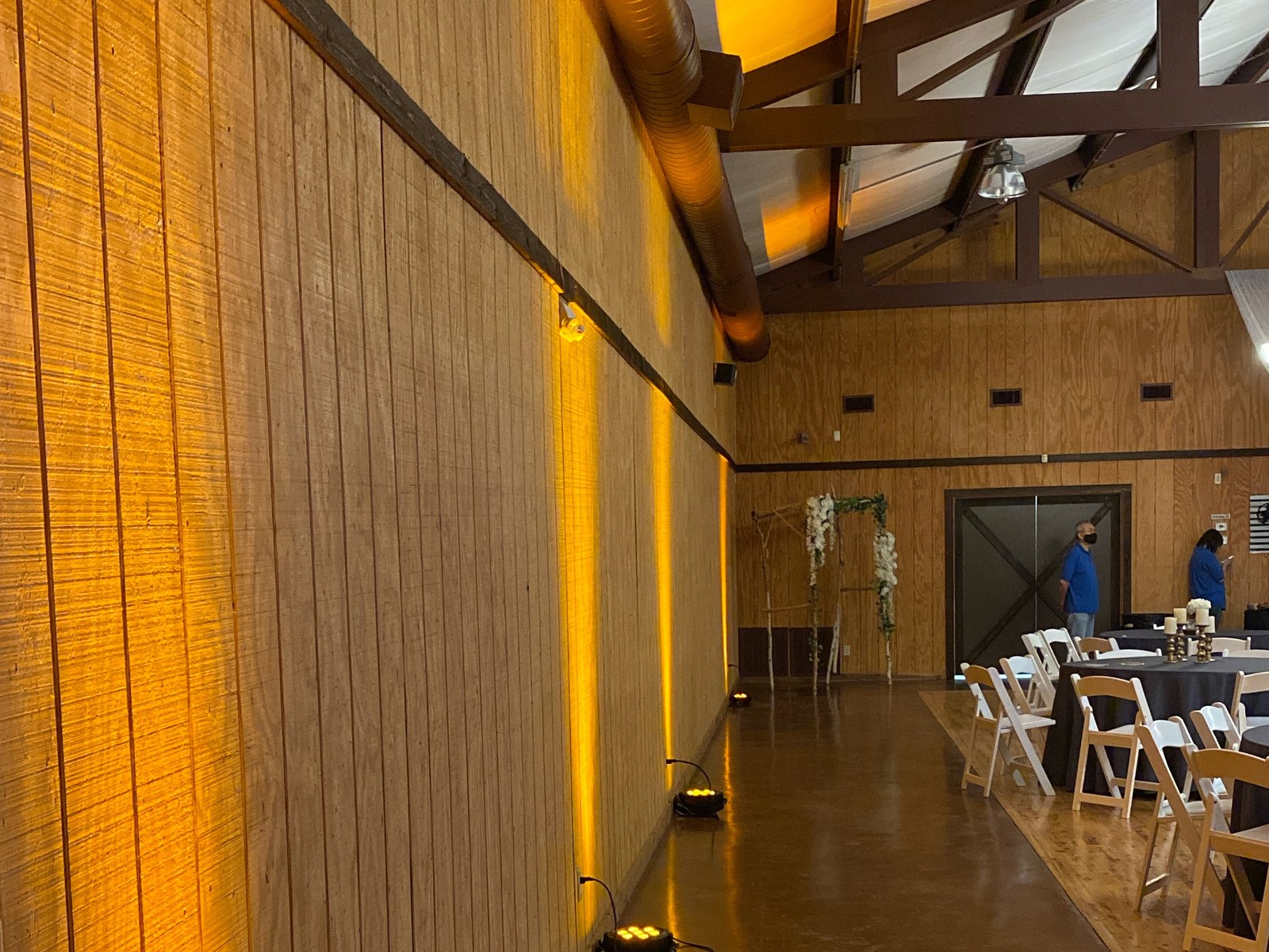 Amber uplighting glowing against a wood plank wall in a barn style event hall