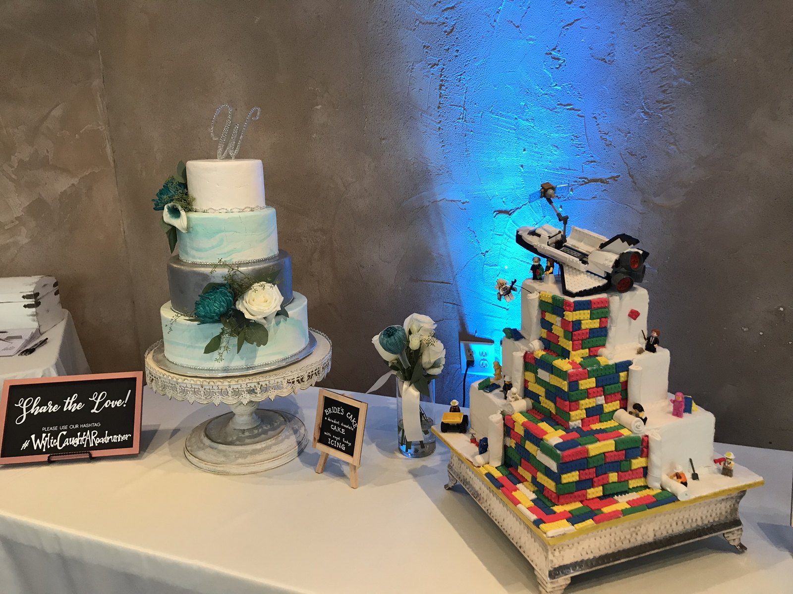 Blue uplighting on a textured wall behind a wedding cake and dessert table
