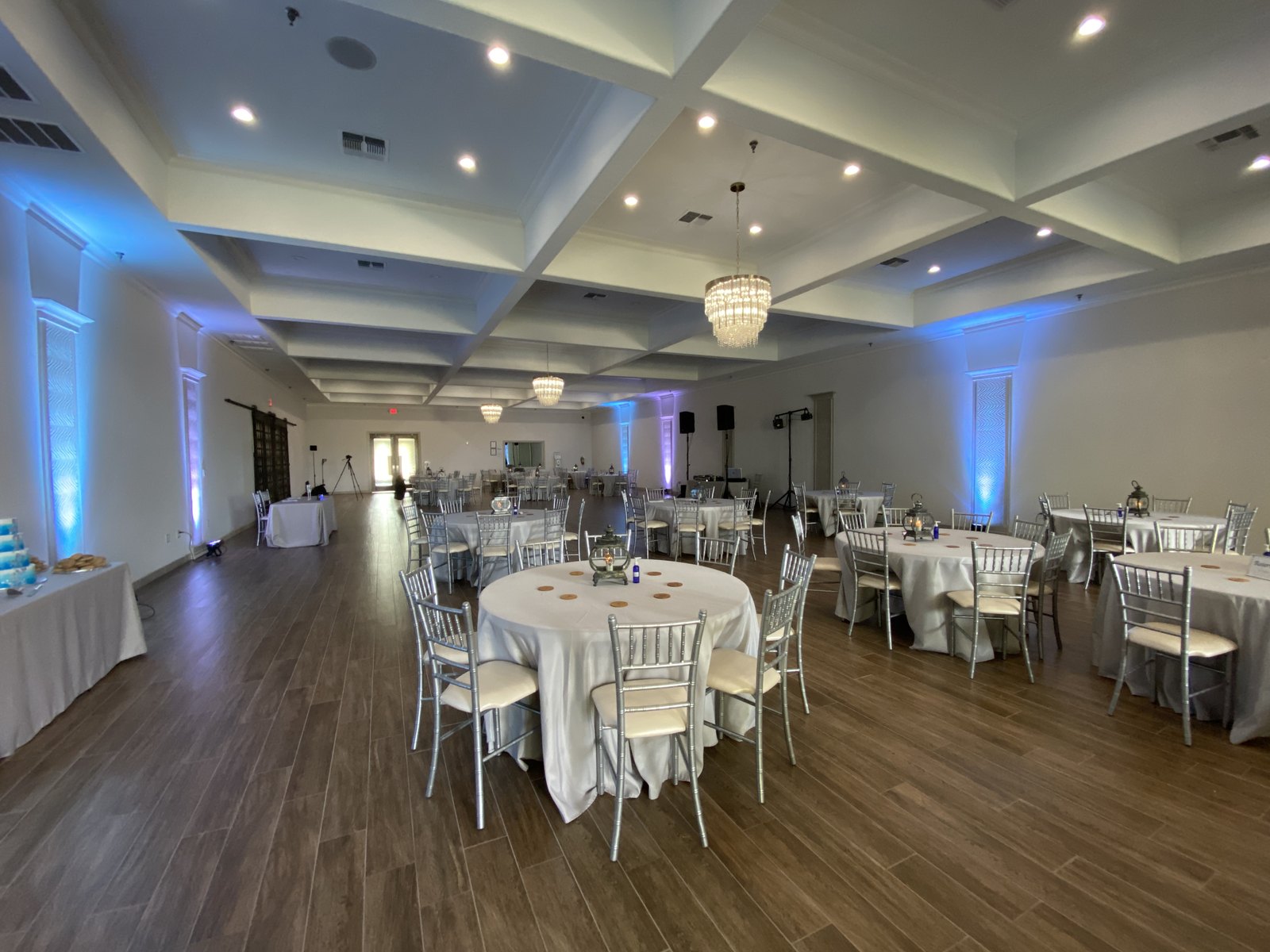 Blue uplighting lining the walls of a white coffered ceiling ballroom set for dinner