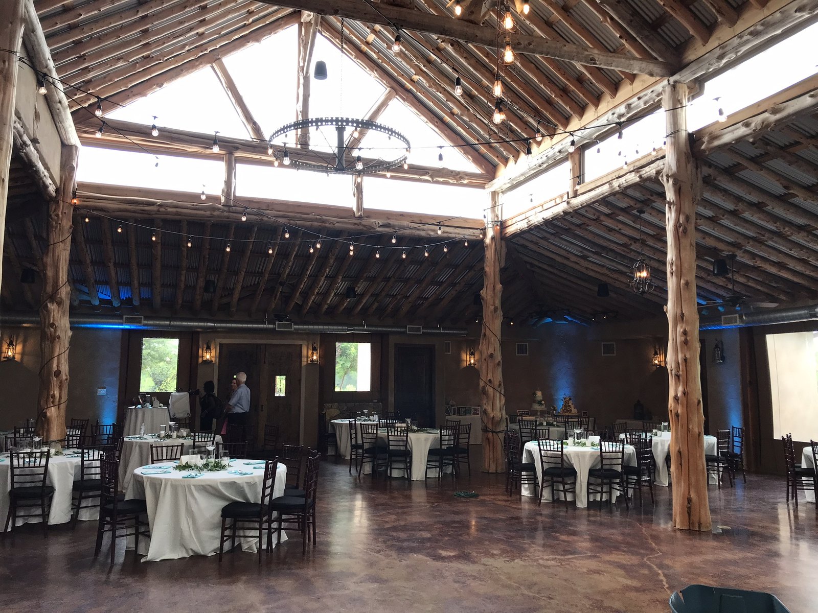 Blue uplighting on the timber posts of a barn venue with daylight still in the windows
