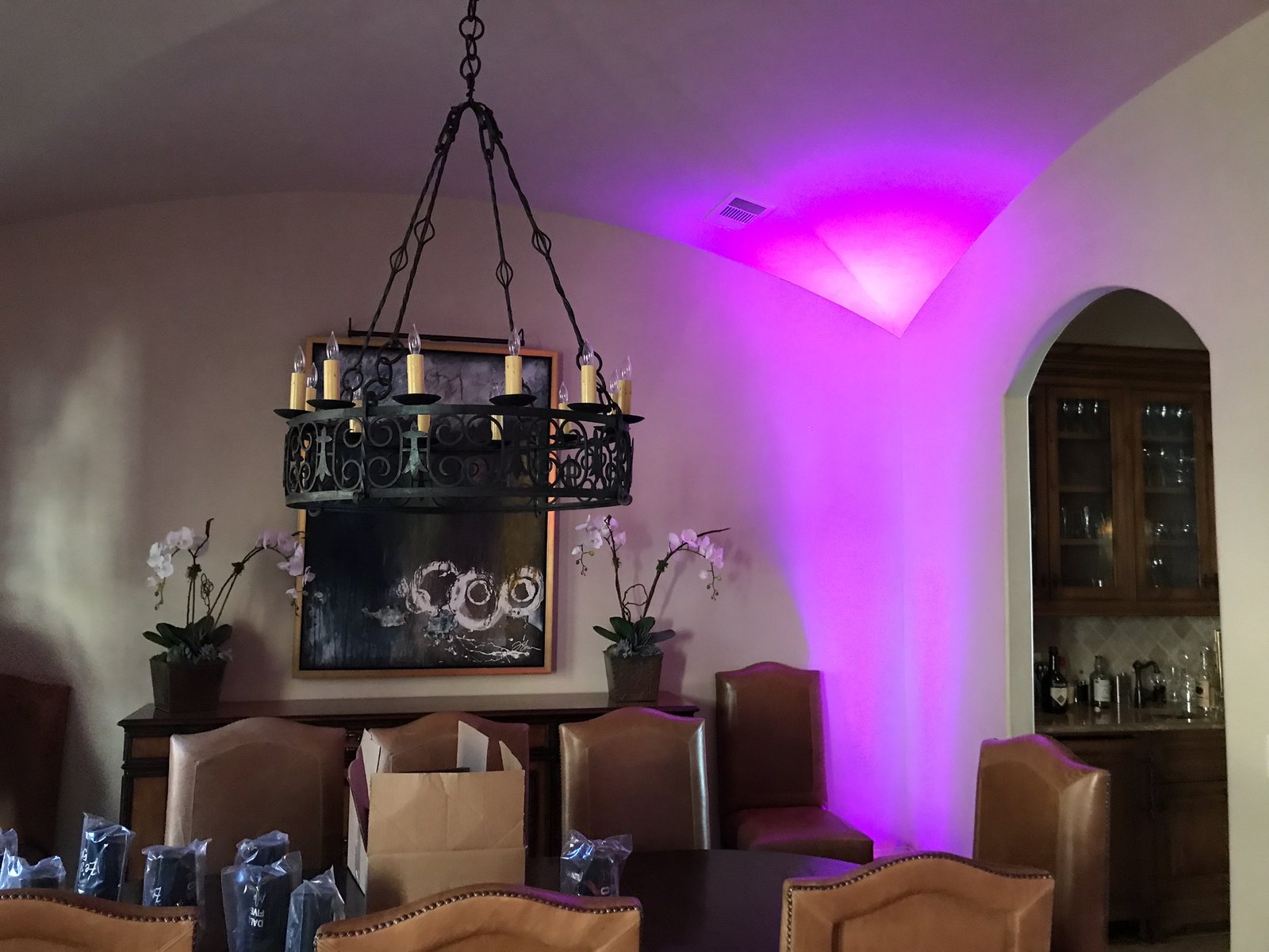 Magenta uplighting filling the corner of a formal room lit by an iron chandelier