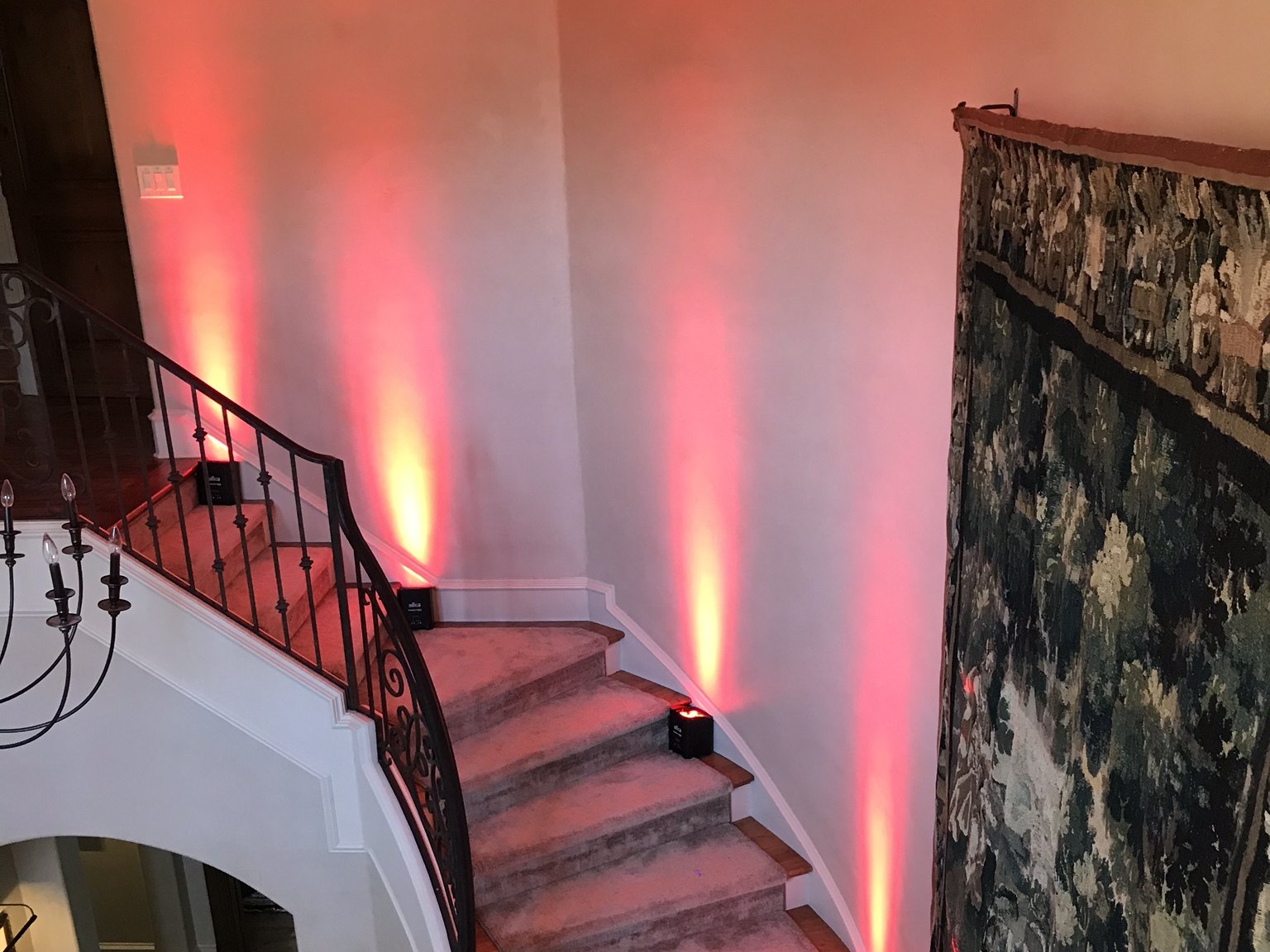 Red uplighting washing a curved staircase and landing in a foyer