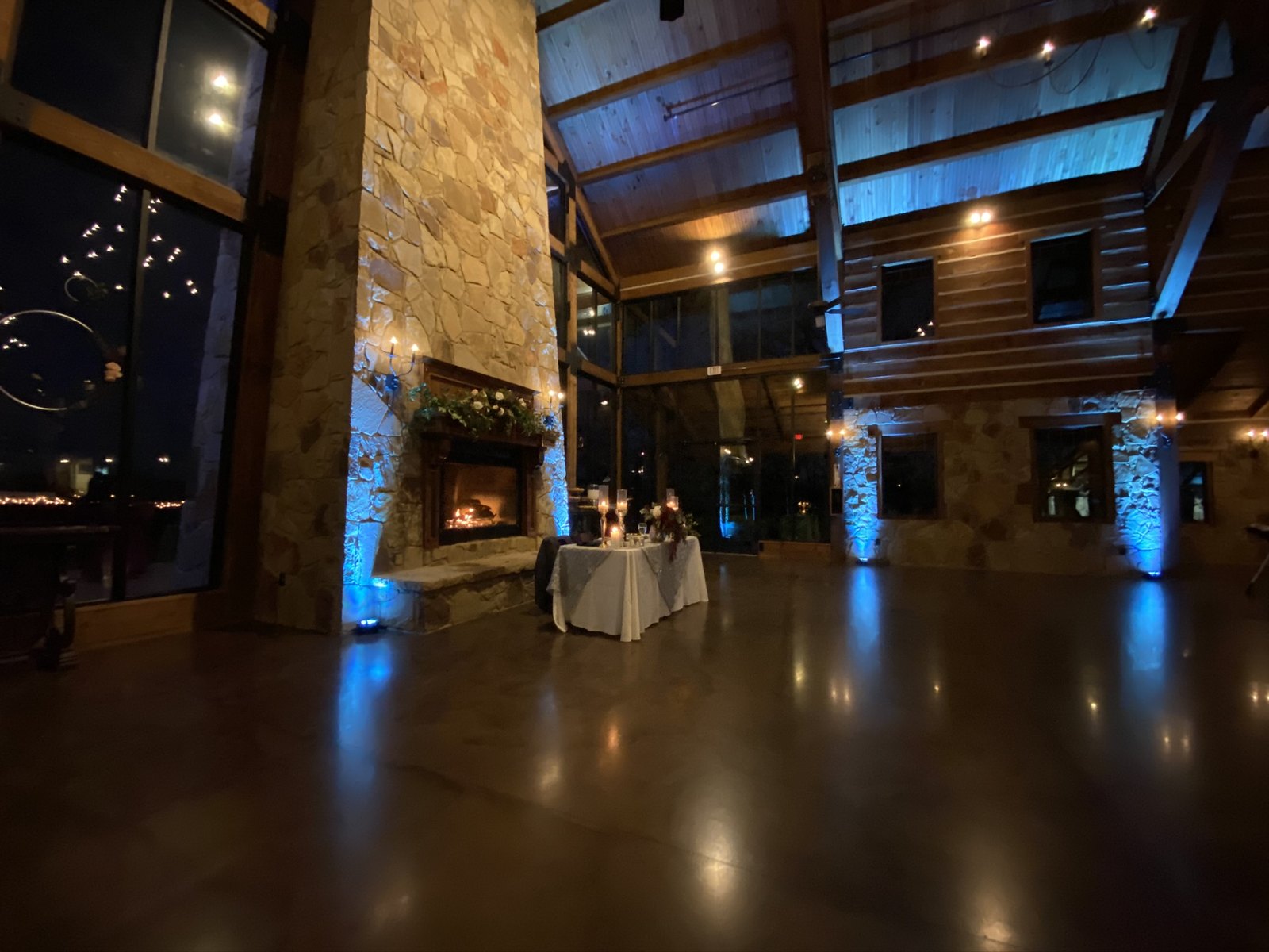 Teal uplighting on a stone fireplace wall in a timber ceiling great room