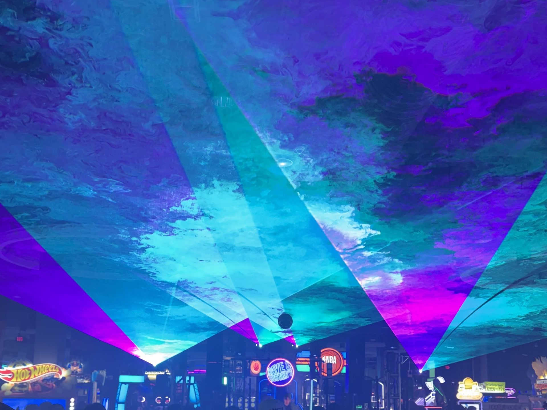 Aerial laser beams fanning out over a standing crowd through haze at a Dallas-Fort Worth rave