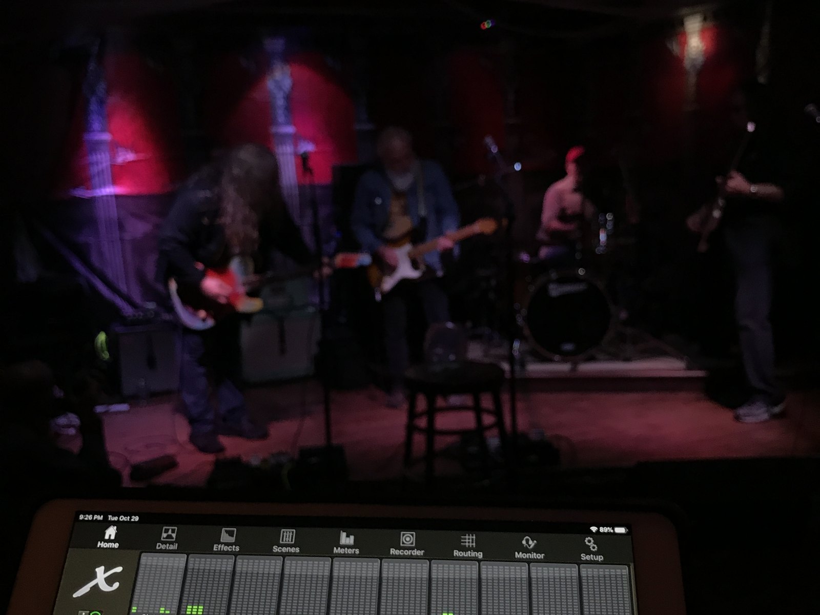 A band playing under red stage light, seen from the mixing position at the back of the room