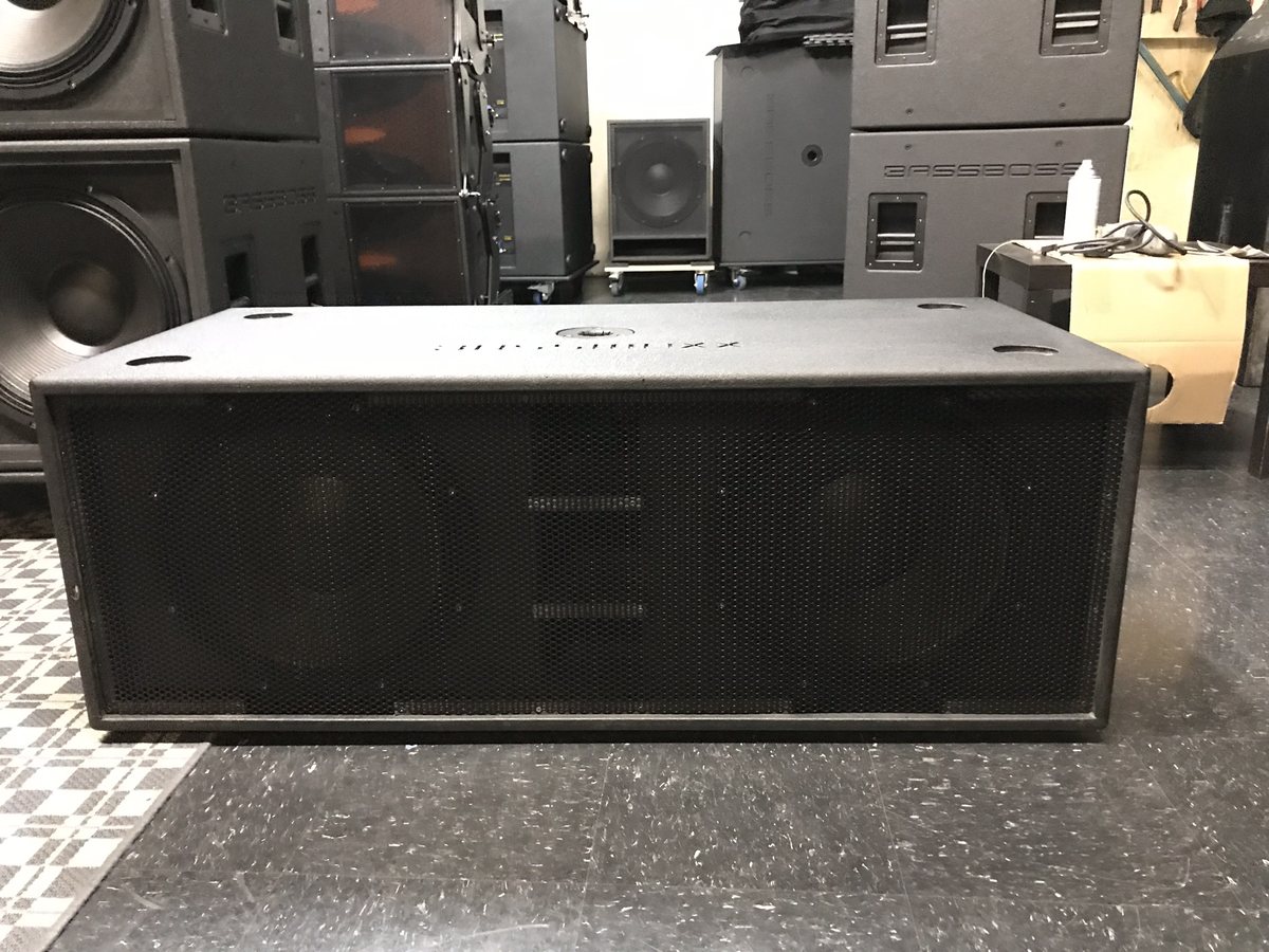 A speaker stack beside a DJ booth set on a patterned floor before doors