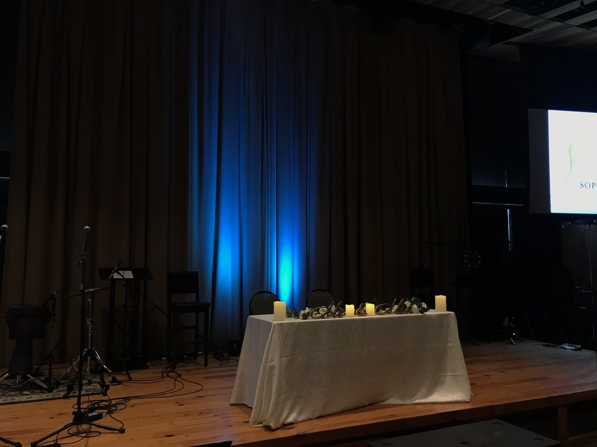 Blue uplighting on a draped wall behind a candlelit head table